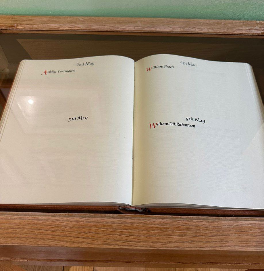 The Book of Remembrance open in its display case, showing names entered under dates in May