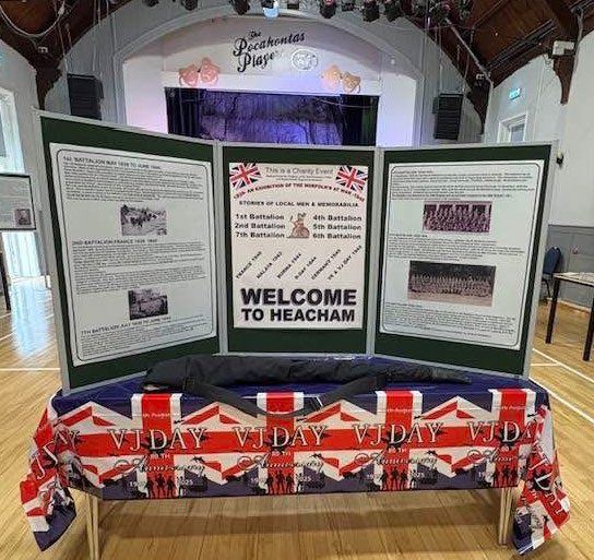 Exhibition display boards headed Welcome to Heacham, above a VJ-Day bunting table