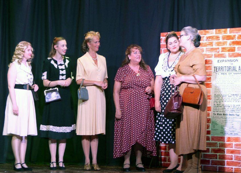 Actors in 1940s dress portraying wives and girlfriends on stage